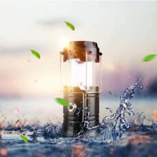 Latarnia kempingowa LED solar Retoo M014A odporna na zachlapanie wodą ustawiona przy rozbryzgu wody o zachodzie słońca – ładowanie solarne