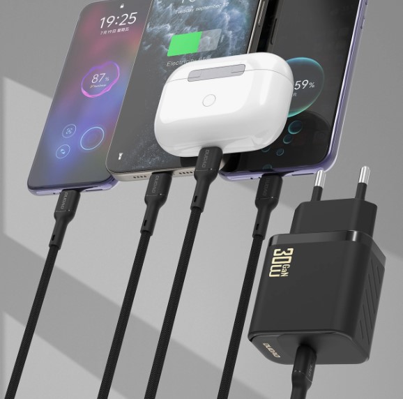 Ładowanie urządzeń mobilnych ładowarką Dudao 30W GaN Czarna ładowarka Dudao 30W GaN z kablami podłączonymi do smartfonów i etui ze słuchawkami bezprzewodowymi.