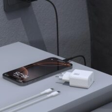 Biała ładowarka Dudao 30W GaN i kabel USB-C leżące na szafce nocnej obok ładującego się telefonu.