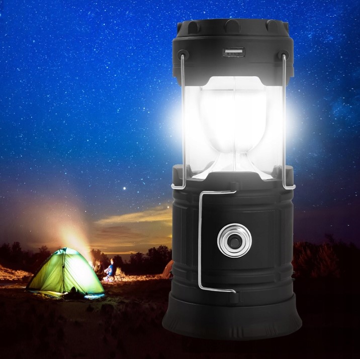Lampa kempingowa Retoo rozsunięta na biwaku Rozsunięta lampa kempingowa świecąca na tle rozgwieżdżonego nieba i oświetlonego namiotu